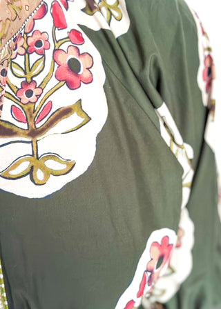 Palm green maxi dress with colorful floral medallion print, orange embroidered trim at neckline, and smocked cuffs