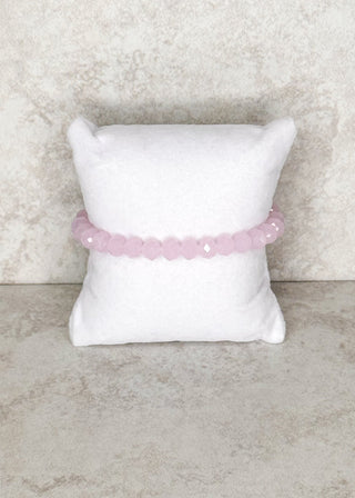 Milky pink beaded bracelet displayed on a stand 