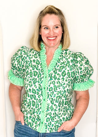 Green animal print blouse with contrast trim, button front, and ruffle sleeves