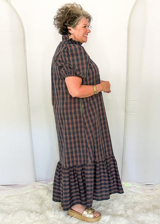 side view of woman wearing a plaid midi dress with puff sleeves and a tiered ruffle hem