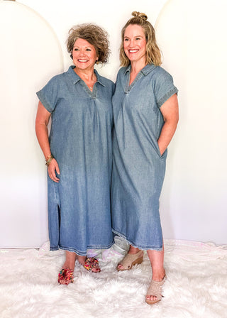 Two women wearing matching blue dresses standing against a white background