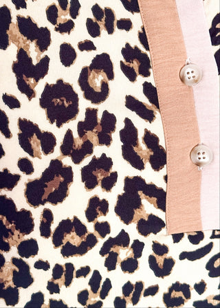close up of leopard print dress with short sleeves, button neckline, and contrast trim in neutral tones