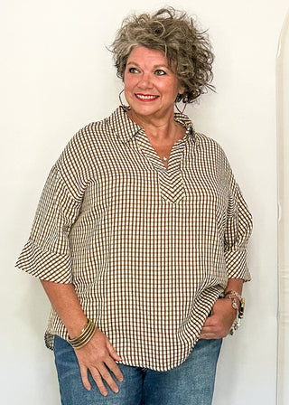 woman modeling a gingham top in brown.