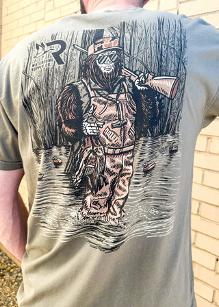 army green tee shirt with sasquatch in waders in the swamp on the back - front pocket