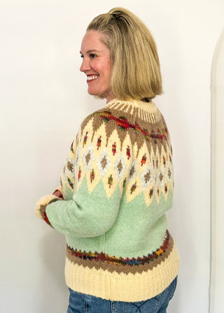 side view of woman modeling a cozy long sleeve sweater with geometric pops of color with a cream and light blue base