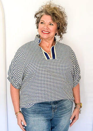 Navy check pattern blouse with contrast white stitching, short dolman sleeves, relaxed shape, and v-split neckline.