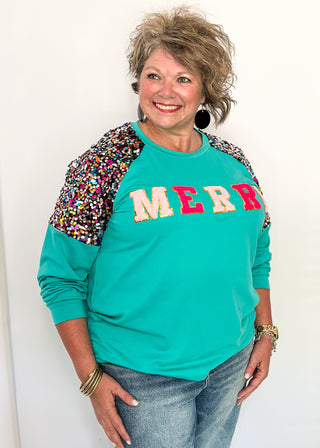 Turquoise long sleeve top with multi color sequin sleeves and chenille ‘MERRY’ lettering across the front.