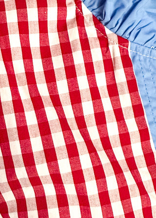 close up of women’s gingham blouse with decorative buttons and statement neckline detail.