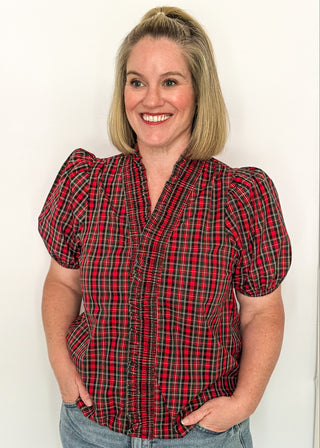 woman wearing a plaid puff sleeve top in red with short sleeves and a V-neckline.