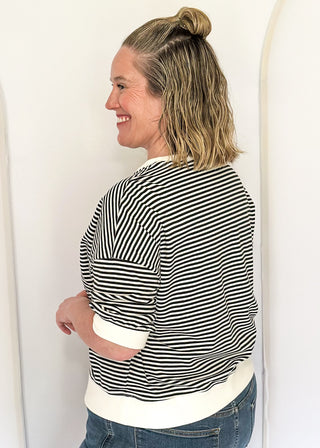 Striped knit dolman top with crew neckline and ribbed trim in black.