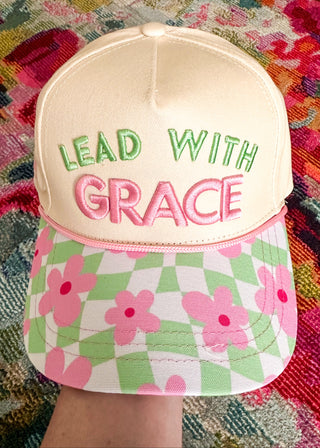 Snap back hat with light green checkered and  pink floral bill with "Lead with Grace" embroidered on the front in light green and pink. 
