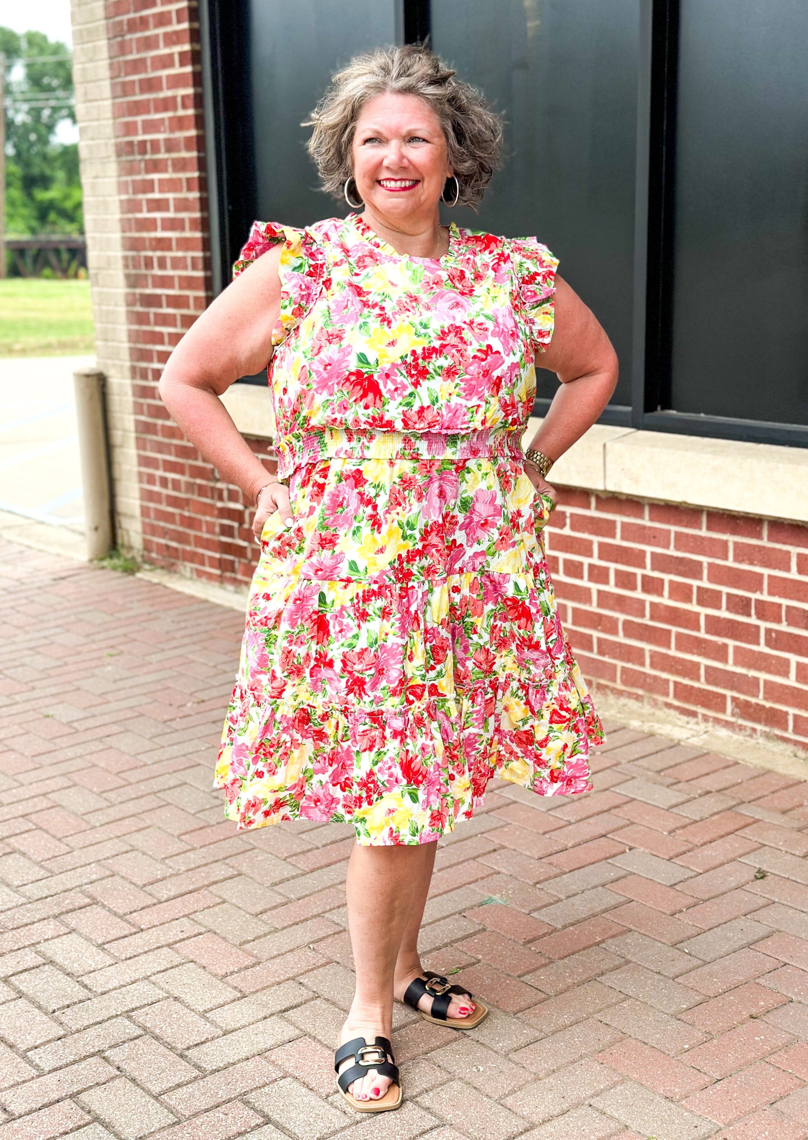 bright floral print smocked waist dress with pockets, ruffle sleeve and neck and one around the bottom  - print colors are yellow, pinks, reds and some green