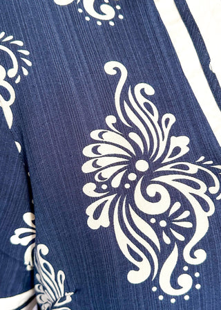 Close up of navy printed short dress with cream contrast trim on the neckline, sleeves, and hem