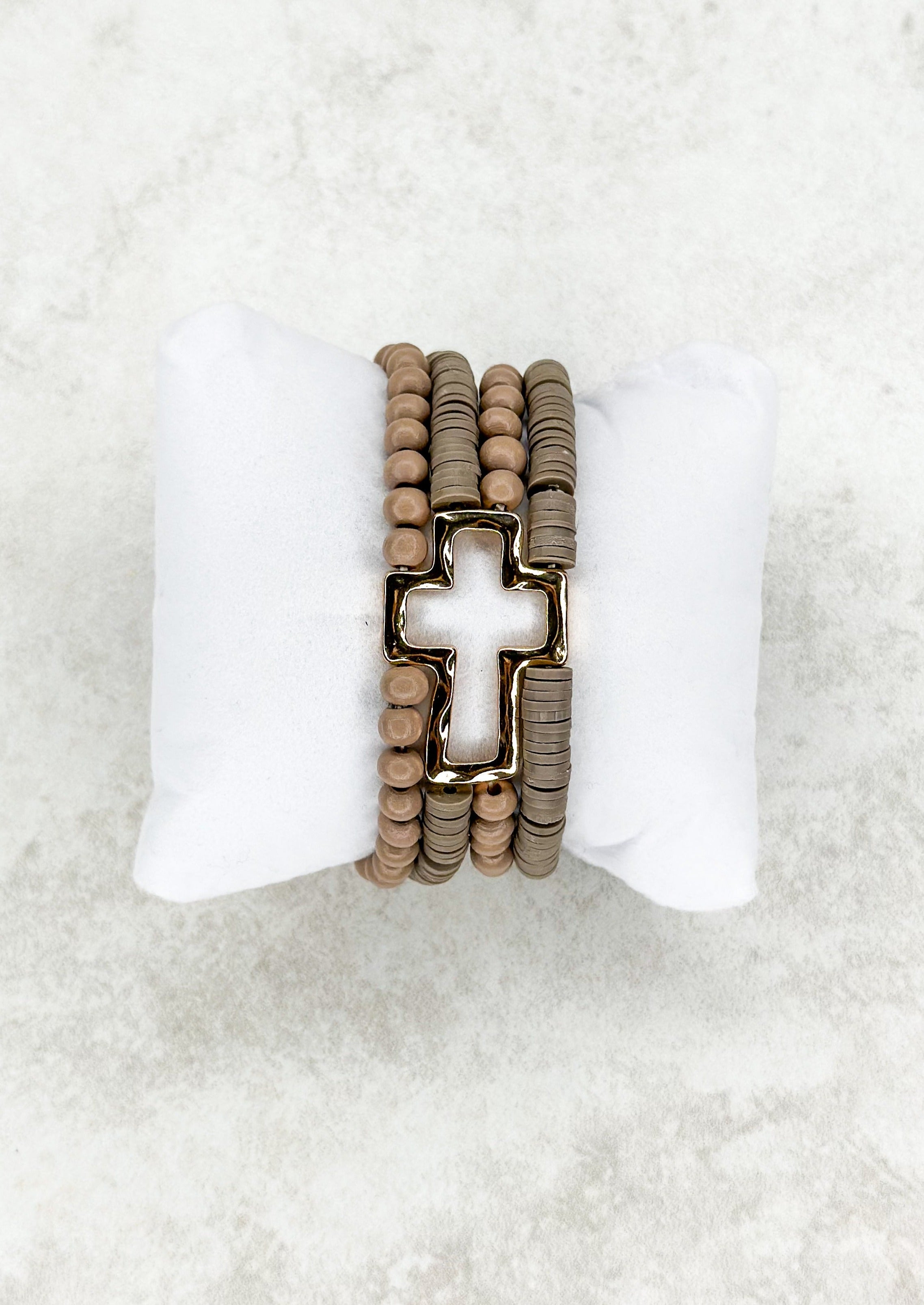 Four strand brown beaded stretch bracelet attached to open gold cross.