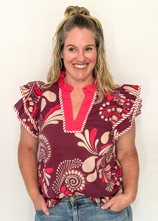 Plum blouse with bold cream and pink florals; flutter sleeves, and striped neckline