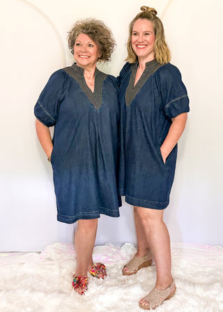 Women's dark blue denim dress featuring statement puff sleeves and contrast stitched detailing around the neckline.