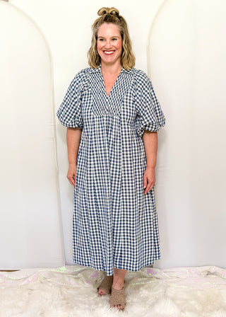 Woman wearing long blue gingham dress with short sleeves