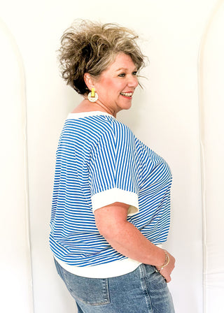 Woman wearing a blue and white striped shirt and jeans against a white background