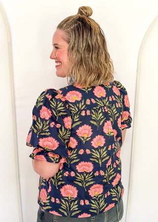Navy floral puff sleeve blouse with pink oversized floral print and striped contrast trim along the neckline and front placket.