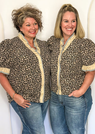 Leopard print blouse with ruffle neckline, puff sleeves, and striped trim.