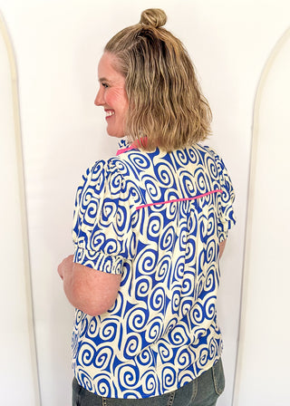 Royal blue swirl print top featuring pink contrast trim, puff sleeves, and lightweight relaxed fit.