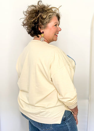 Lightweight cream long-sleeve top with colorful chenille patch letters spelling “HAPPY”