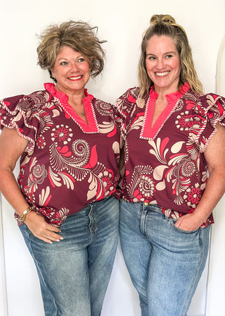 Plum blouse with bold cream and pink florals; flutter sleeves, and striped neckline
