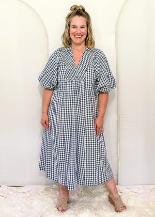 Woman wearing long blue gingham dress with short sleeves