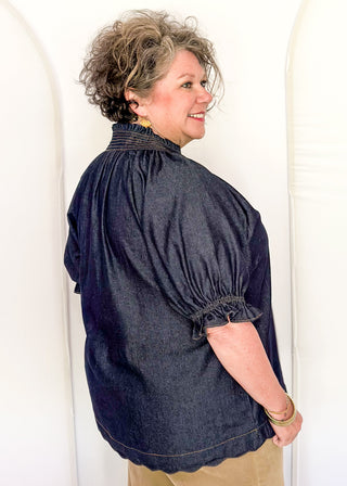 Women's indigo denim-look blouse featuring a smocked split neckline, puff sleeves, and a relaxed fit.