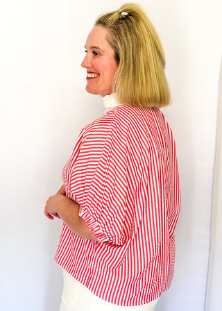 Striped seersucker top in pink and white with short sleeves, relaxed fit, and split neckline.