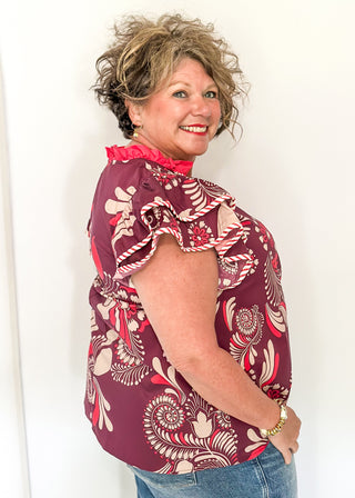 Plum blouse with bold cream and pink florals; flutter sleeves, and striped neckline