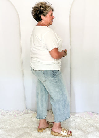 side view of woman wearing denim crop jeans and white tee.