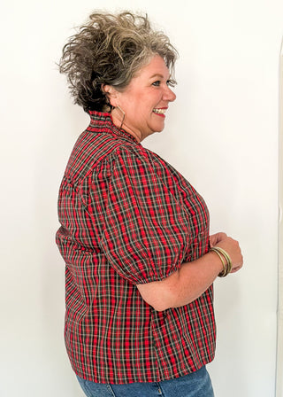 side view of woman wearing a plaid puff sleeve top in red with short sleeves and a V-neckline.