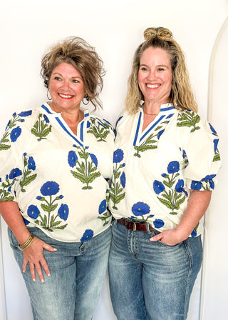 3/4 smocked sleeve white top with large blue blooms. V-neck with blue piping detail. 