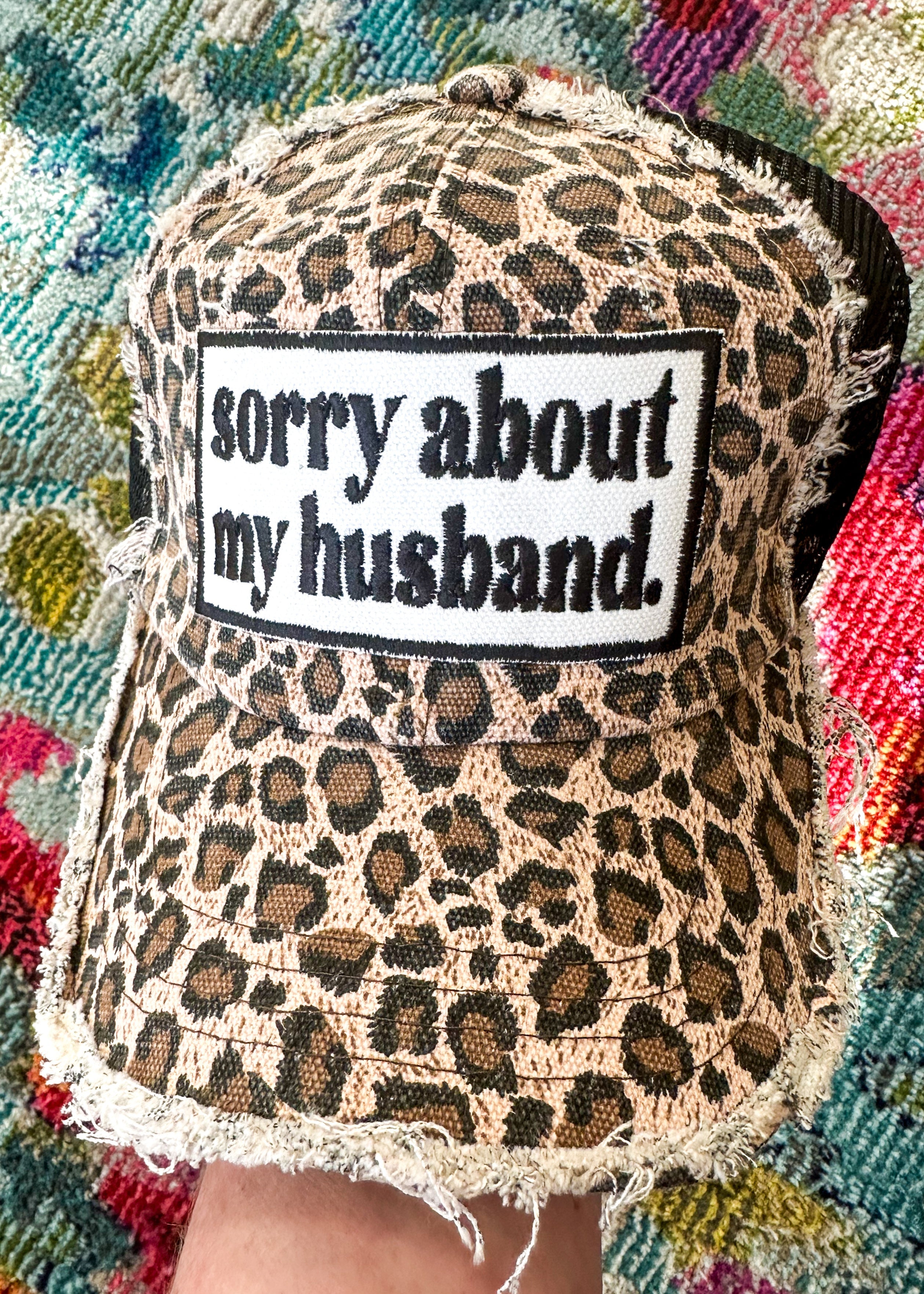 "sorry about my husband" embroidered patch in black on leopard trucker hat and black mesh.

Velcro Back