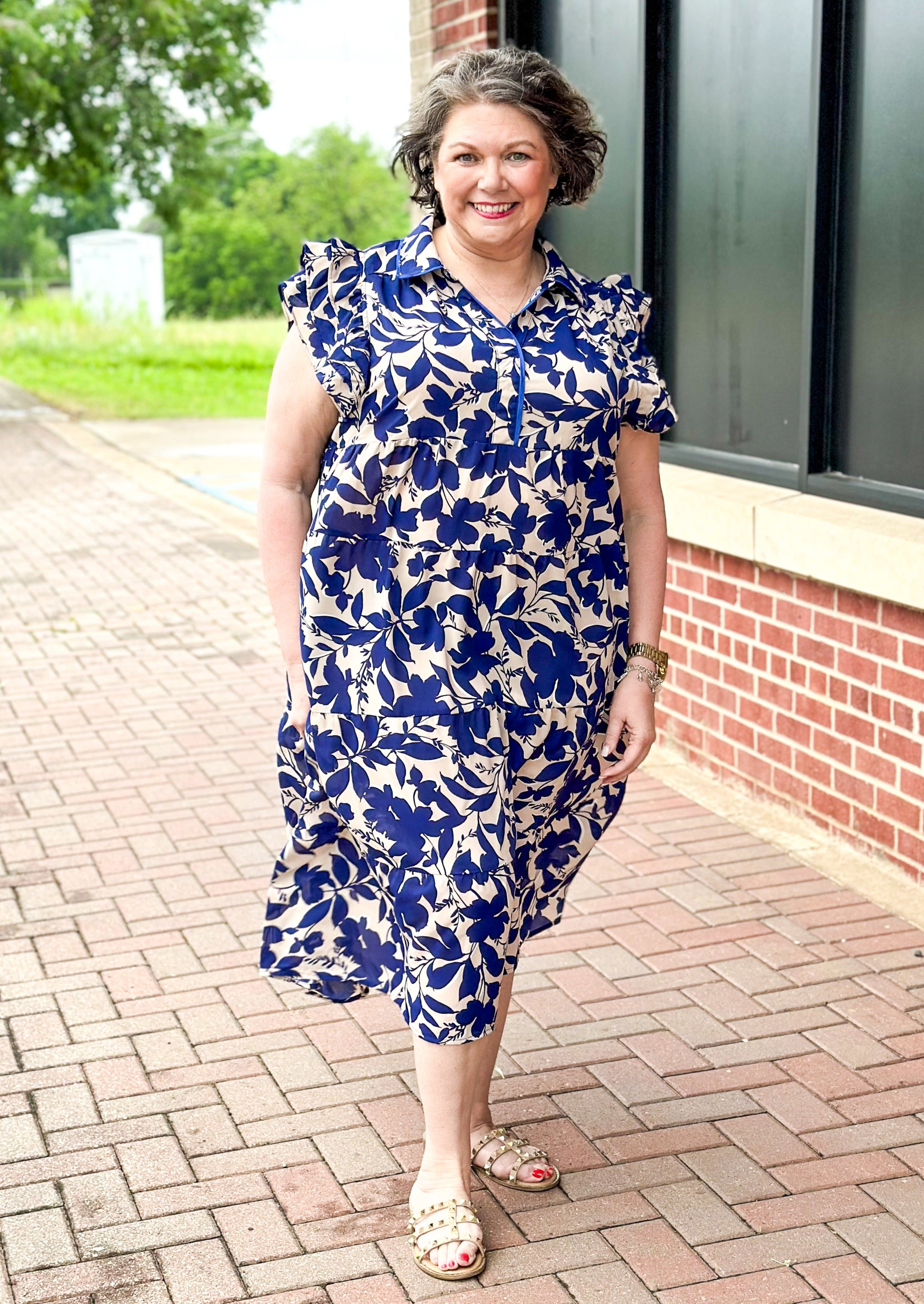 Navy floral tiered midi dress on light tan background - collar - multi ruffle sleeve - piping detail on top