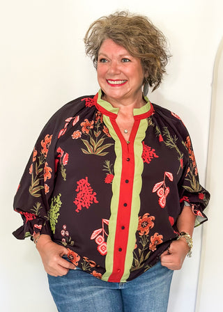 black button up long sleeve top with red flowers and greenery - red and green scalloped stripe detail along collar and down front 