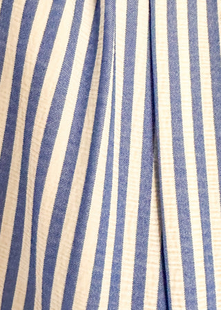 close up of sleeveless dress with vertical blue and white stripes. v neck and smocked waist