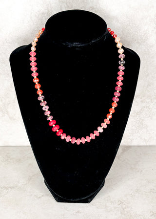 Pink beaded necklace displayed on a black neck form 