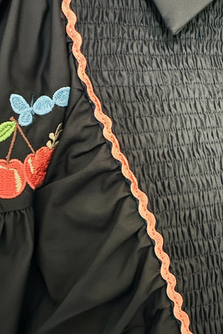 close up of black midi dress with embroidered puff sleeves and a smocked bodice