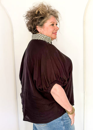 Women's black top featuring a gingham contrast neckline, loose silhouette, and subtle puff sleeves