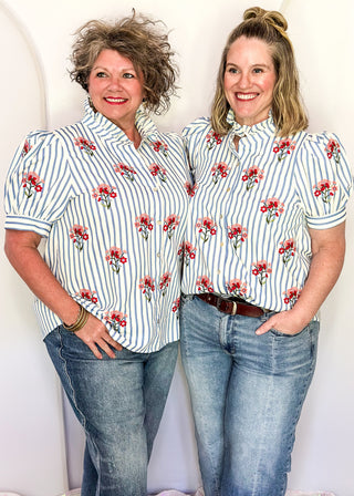 Short sleeve button up top with blue stripes and embroidered floral bundles in red and pink. 