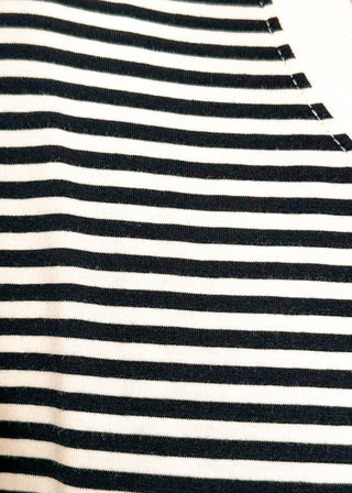 Close up of black and white striped short sleeve top with white banding on sleeve and collar. 