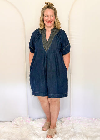 Women's dark blue denim dress featuring statement puff sleeves and contrast stitched detailing around the neckline.