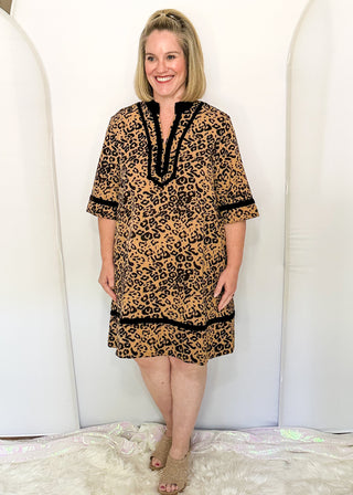 woman modeling a leopard print dress with black velvet contrast.