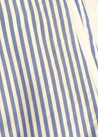 Close up of striped seersucker top in light blue and white with short sleeves, relaxed fit, and split neckline.