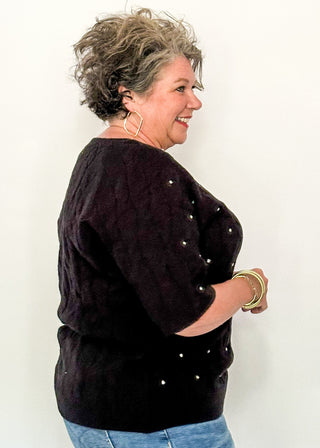 side view of woman wearing black sweater with rhinestones