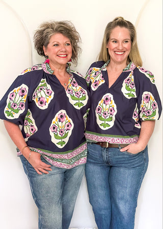 Women’s short sleeve floral blouse in navy with contrast neckline detail, and decorative hem