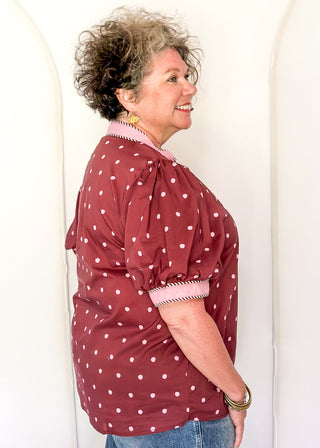 woman wearing burgundy button up top with polka dots.