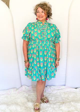 Mint green floral dress with colorful pink flowers, featuring short puff sleeves, ruffled neckline, smocked waist, and flowy skirt.